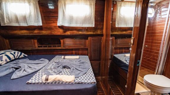 Interior view of a cabin with double bed, mirror, and adjoining bathroom on Gulet Thalasa.