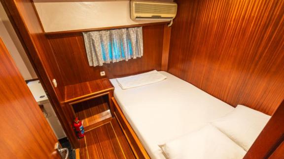 Second guest cabin of Gulet Esperanza featuring a double bed, wood paneling, and an air conditioning unit above the wind