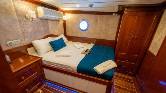 A cosy cabin on the gulet Queen of RTT in Fethiye, equipped with a comfortable double bed, blue bed linen and stylish wo