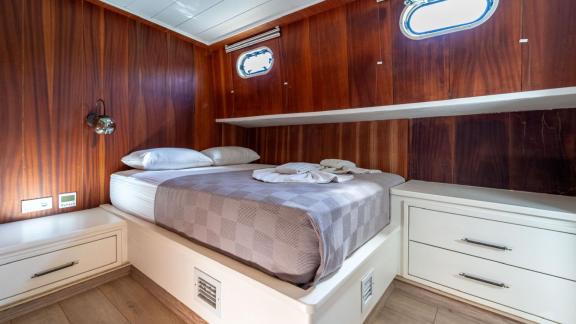 The stylish cabin of Gulet ÇağAy features a comfortable double bed, wooden paneling, and practical drawers.