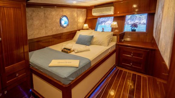 A guest cabin on the gulet Queen of RTT in Fethiye, equipped with a comfortable double bed, blue bed linen and stylish w