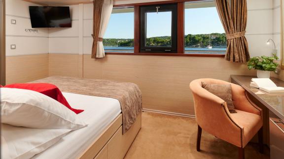 Comfortable cabin with large window and desk on the motor yacht Queen Eleganza