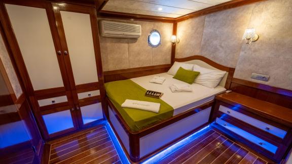 Cosy cabin on the gulet Queen of RTT in Fethiye with a comfortable double bed, green bed linen and stylish wooden furnit