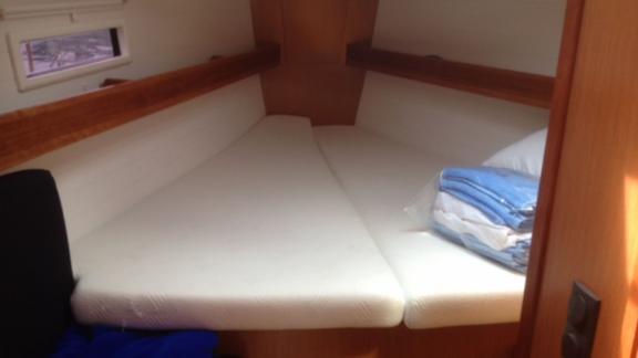 The bow cabin of sailing yacht Almina features a spacious bed with white linens.