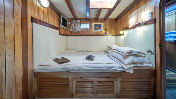 Cosy bedroom on a gulet with wooden interior, double bed, skylight and small TV.