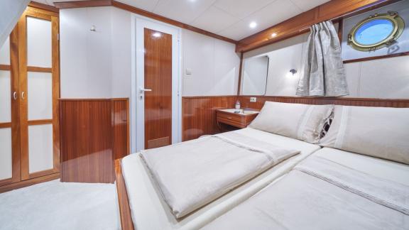 Gemütliches Schlafzimmer mit Doppelbett, Schrank und Bullauge auf einer 9-Kabinen-Gulet aus Split.