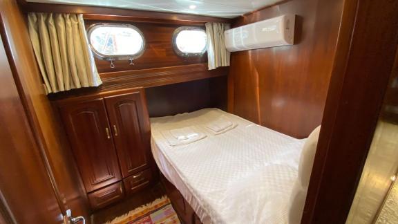 Каюта с двуспальной кроватью, двумя иллюминаторами и элегантной деревянной отделкой на гулете Be Happy в Бодруме.