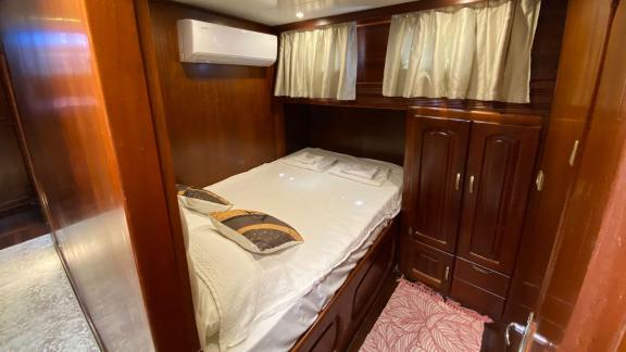 Каюта с двуспальной кроватью, занавесками и роскошным деревянным интерьером на гулете Be Happy в Бодруме.