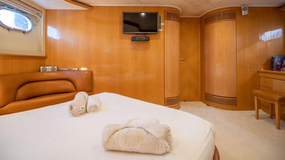 Das Schlafzimmer der Motoryacht Lady L zeigt einen Wandfernseher und einen bequemen Sitzbereich.