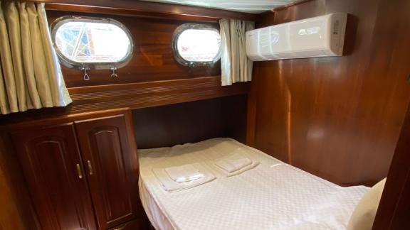 Каюта с двуспальной кроватью, двумя иллюминаторами и элегантным декором на гулете Be Happy в Бодруме.