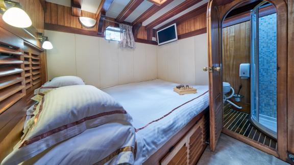 Cosy bedroom on a gulet with double bed, small TV and private bathroom.