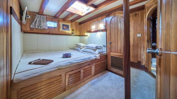 Cosy bedroom on a gulet with wooden interior, double bed and skylight.