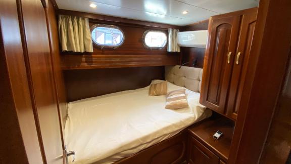 Каюта с двуспальной кроватью, двумя иллюминаторами и элегантной деревянной отделкой на гулете Be Happy в Бодруме.