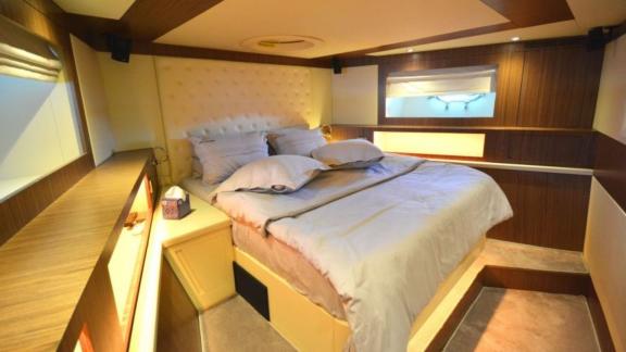 Cozy sleeping cabin with a double bed and stylish interior on a motor yacht.