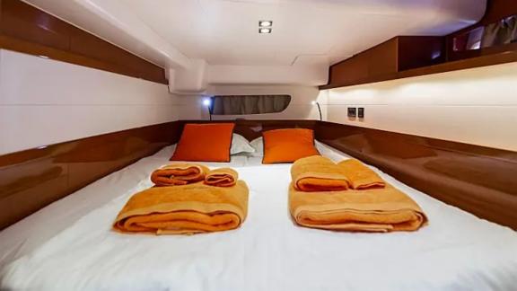 The cozy cabin of the Tourbillon yacht offers a warm atmosphere with orange pillows and towels.