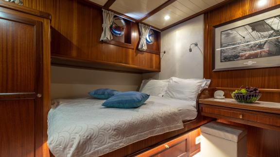 A cosy cabin on board the Gulet Smart Spirit with a comfortable bed and stylish wooden furnishings.