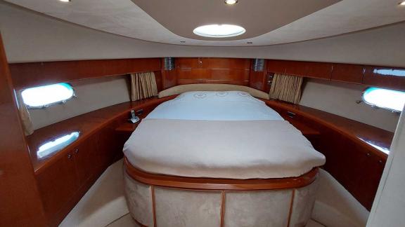 The front cabin of the yacht Cielo features a luxurious bed, wooden furniture, and windows.