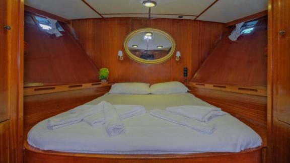 Cozy cabin on the trawler Grainne Mhaol with a double bed and wooden details.