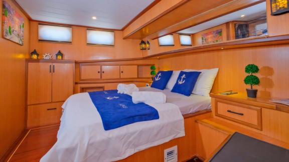 Cabin on Gulet Anes with a double bed, blue linens, and stylish nautical decor.