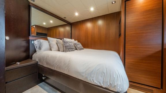 The cabin of the motor yacht Aya One features a cozy double bed and wooden details, providing a comfortable sleeping are