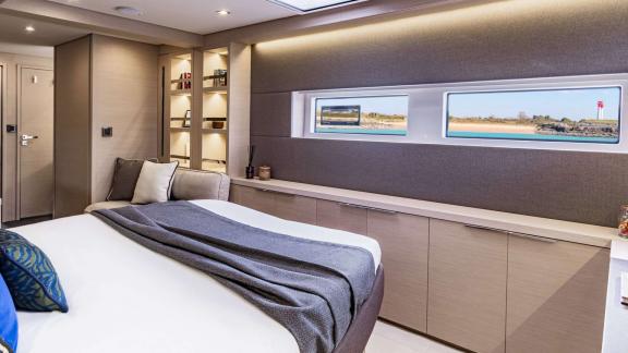 The spacious bedroom of catamaran Happy offers a comfortable experience with large windows and modern design.