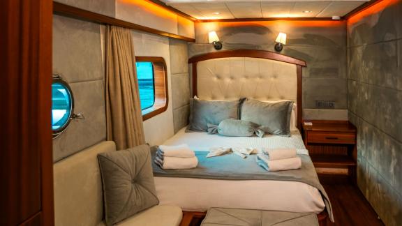 Elegant and cozy guest cabin with a wide window on board the Oggusto trawler yacht.