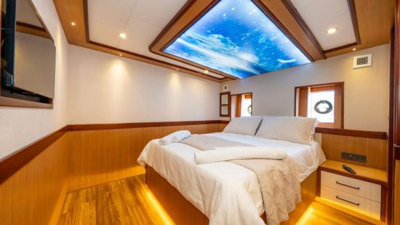 Large bed and sky-themed ceiling light in Lila yacht cabin near Fethiye.