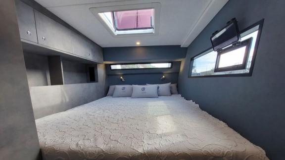 Cozy, scenic cabin aboard the Luna 47 Power catamaran named Orange, with a large bed and windows.