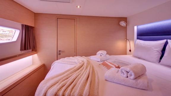 Helidoni charter catamaran features a peaceful cabin with window and warm lighting.