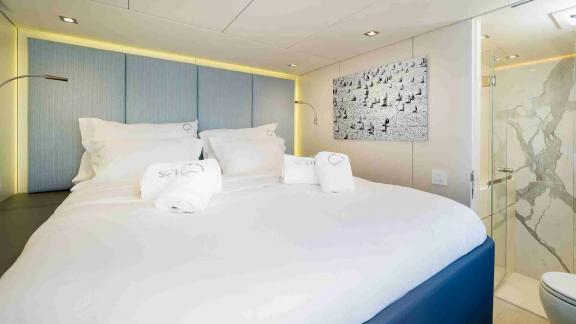 The cozy cabin of Sunreef 50 Solitaire features ambient lighting, a spacious bed, and a private marble bathroom.