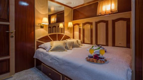 The cozy cabin of Korab motor yacht features rich wood and warm ambient lighting.