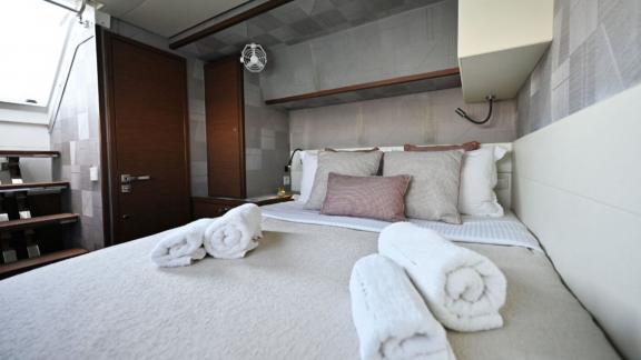 The double cabin of Ace of Hearts in Athens features a large bed, towels and wooden cabinets.