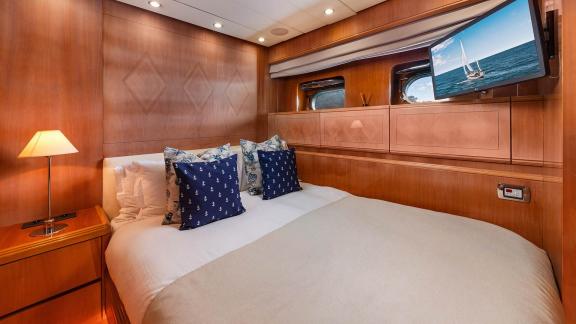 The double cabin of Dream motor yacht in Athens features a double bed, TV unit and wooden cabinets.