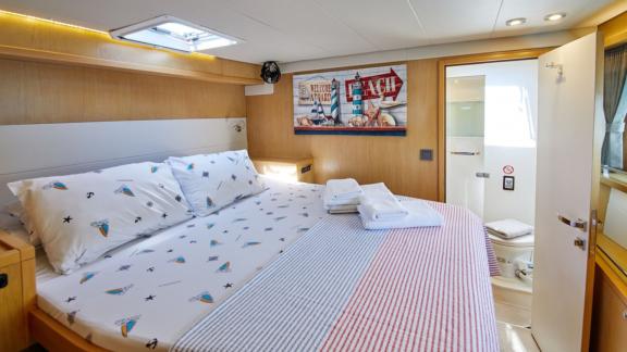 The spacious master cabin on the catamaran Pata is equipped with a comfortable bed and a private bathroom.