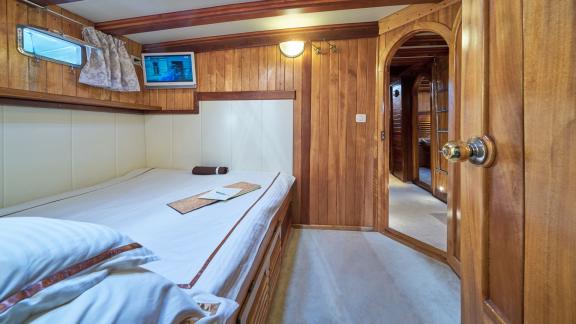 Cosy bedroom on a gulet with wooden interior, double bed and small TV.