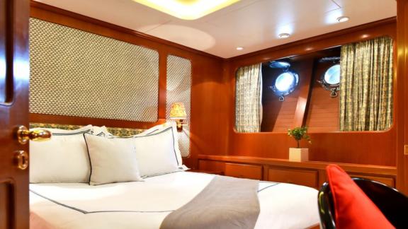 Стильная гостевая каюта Tamarita с удобной двуспальной кроватью и иллюминаторами.