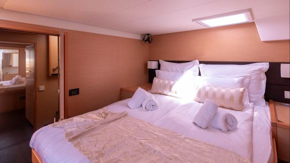 This Lagoon 560 Topaz cabin offers a peaceful sleeping space with natural light and a spacious interior design.