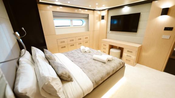 Modern bedroom on Princess Melda yacht with large windows and comfortable furniture.