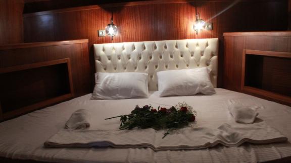 The stylish bed in the cabin of Gulet Life is Life, decorated with roses for a romantic atmosphere.
