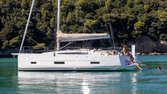 The sailboat Joy 5 is anchored while passengers swim in the sea.