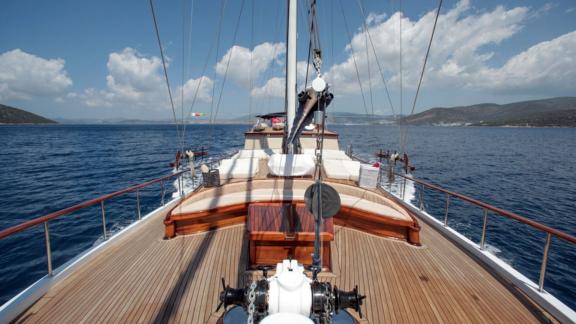 Blick auf das geräumige Deck der Gulet Dulcinea, segelnd in den blauen Gewässern von Bodrum unter einem wolkigen Himmel.