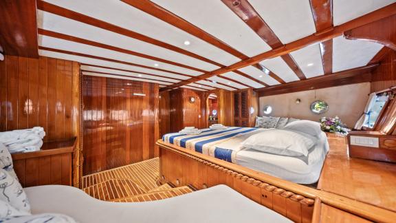 Die Hauptkabine mit Holzinterieur bietet ein großes Bett, eine Sitzecke und Fenster mit Meerblick.