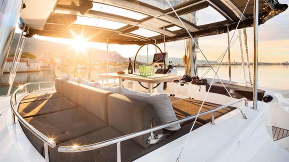 Cozy cockpit with a couch, dining table, and steering wheel, illuminated by the setting sun.