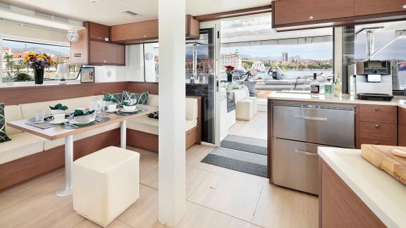 Stylish dining area with a set table and a modern kitchen, overlooking the outer deck and the sea.