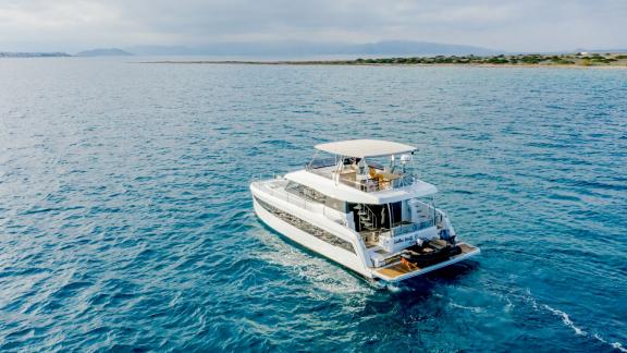 The Endless Beauty catamaran glides over calm seas near the coast of a Greek island.