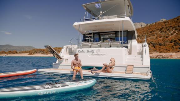 A couple enjoys watersports and relaxation on the Endless Beauty against a coastal backdrop.