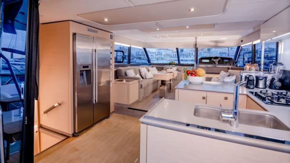 Bright, well-equipped kitchen and cozy living area on a luxurious catamaran, with large windows and stylish design.