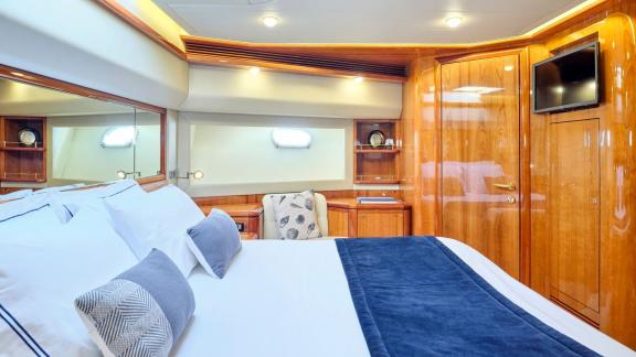 Elegant bedroom with a large bed, wood paneling, and TV in a luxury yacht cabin