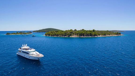 Horizon Elegance 115 Conte Stefani is captured from above while anchored near picturesque island landscapes.