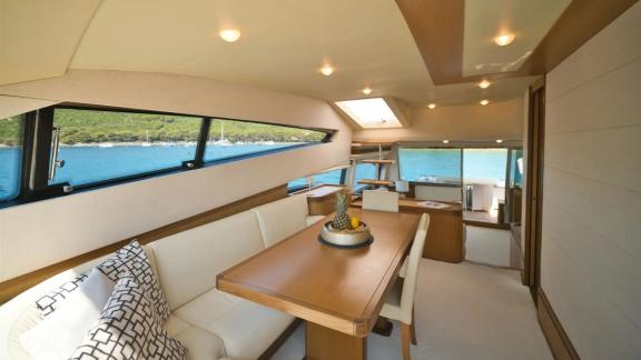 Ferretti 681 Dominique features a dining table, seating area and large windows overlooking the sea.